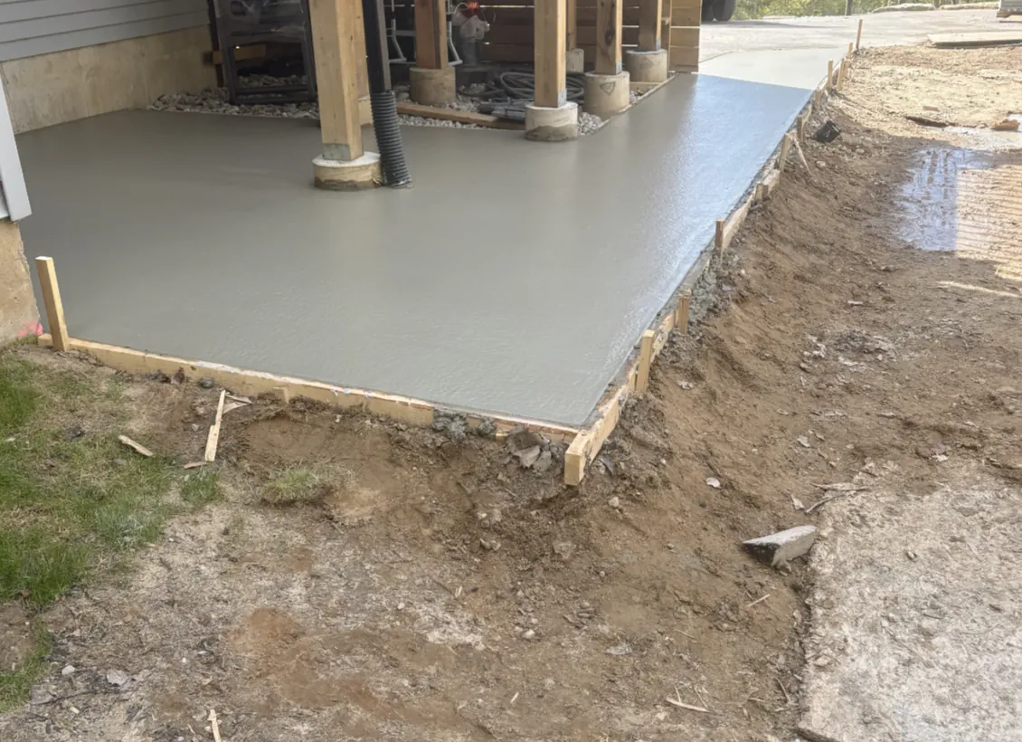 Concrete? Of Course! freshly poured and finished concrete slab beside porch posts
